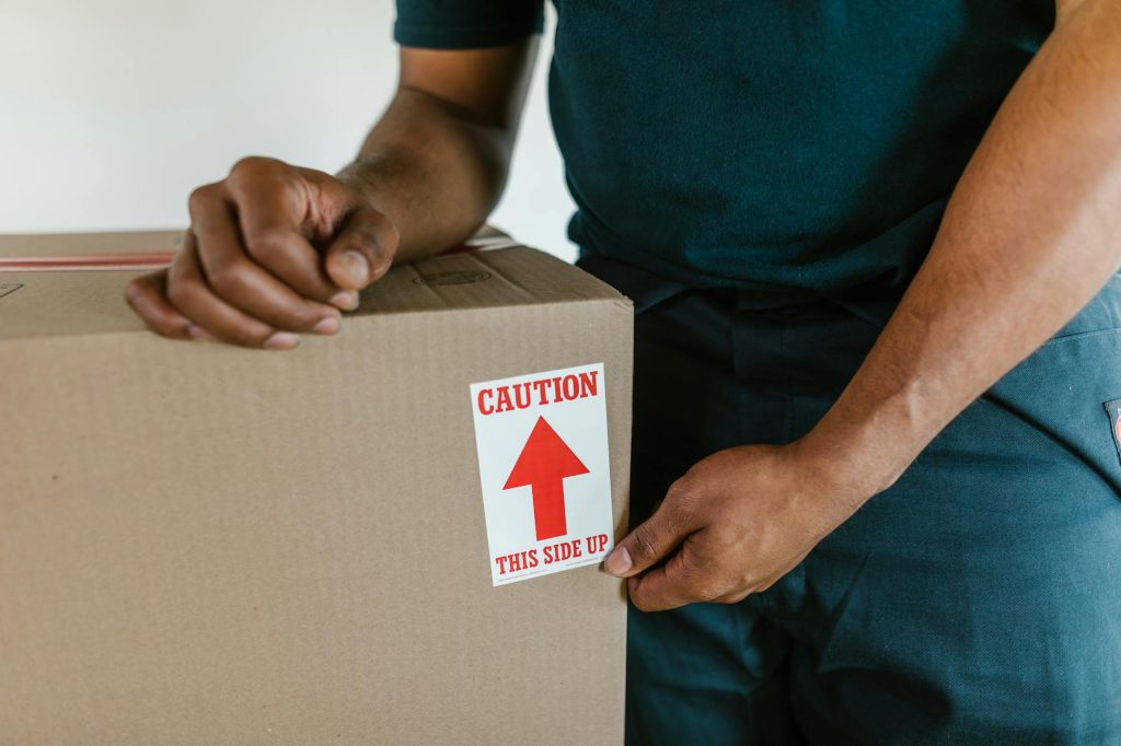 Several movers carry furniture into a moving truck, with one on the tailgate.