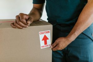 Two professional movers in blue shirts carrying a large box inside a home.